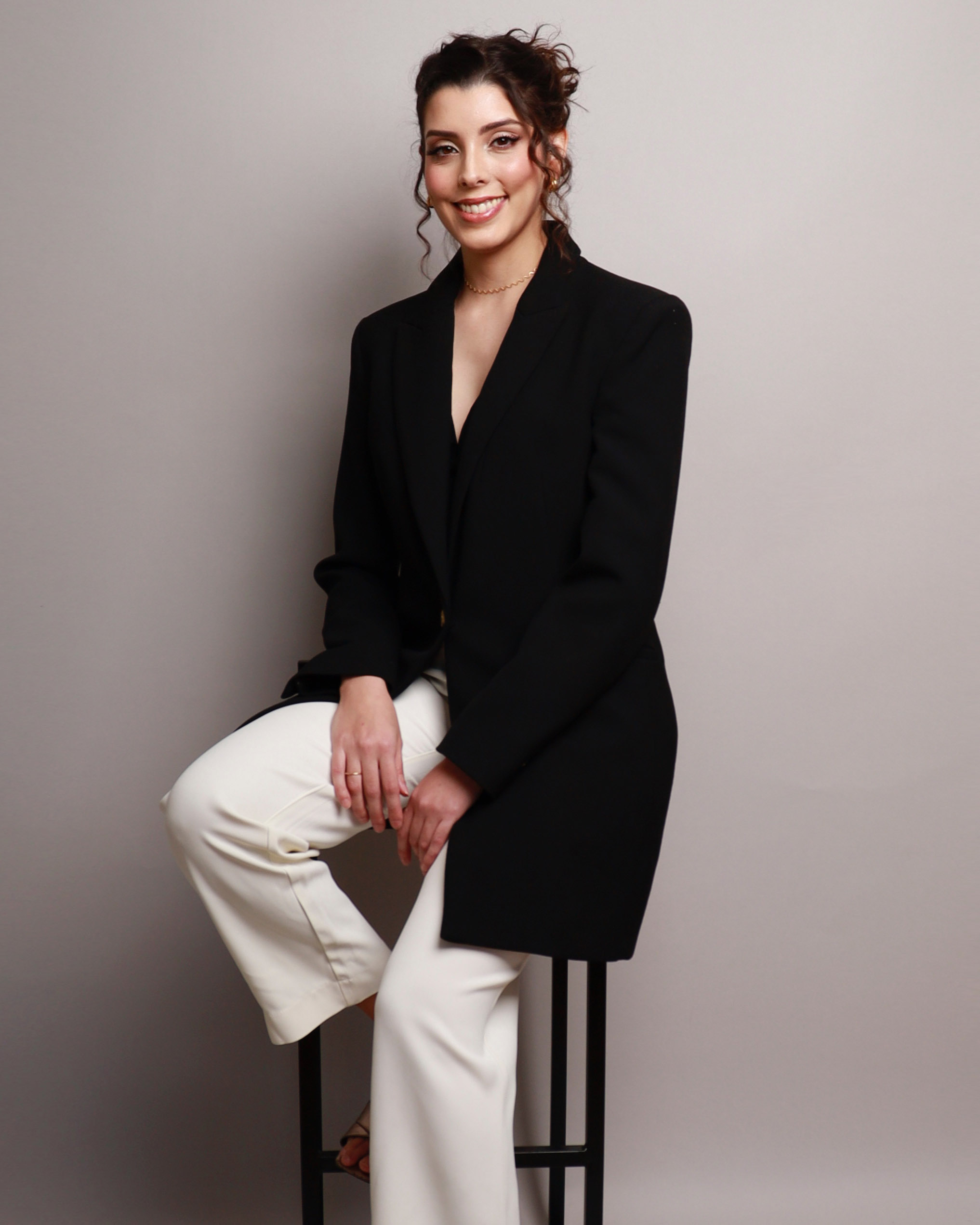 Dra. Isabella Motta sentada em banco sorrindo.